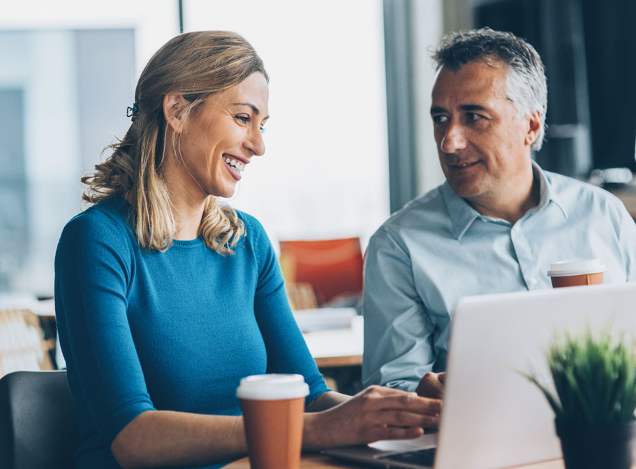 Two people sitting in front of a laptop, smiling